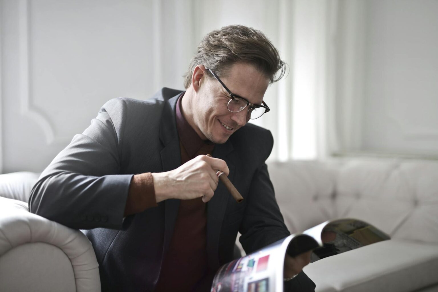 elegant businessman with cigar reading magazine at home