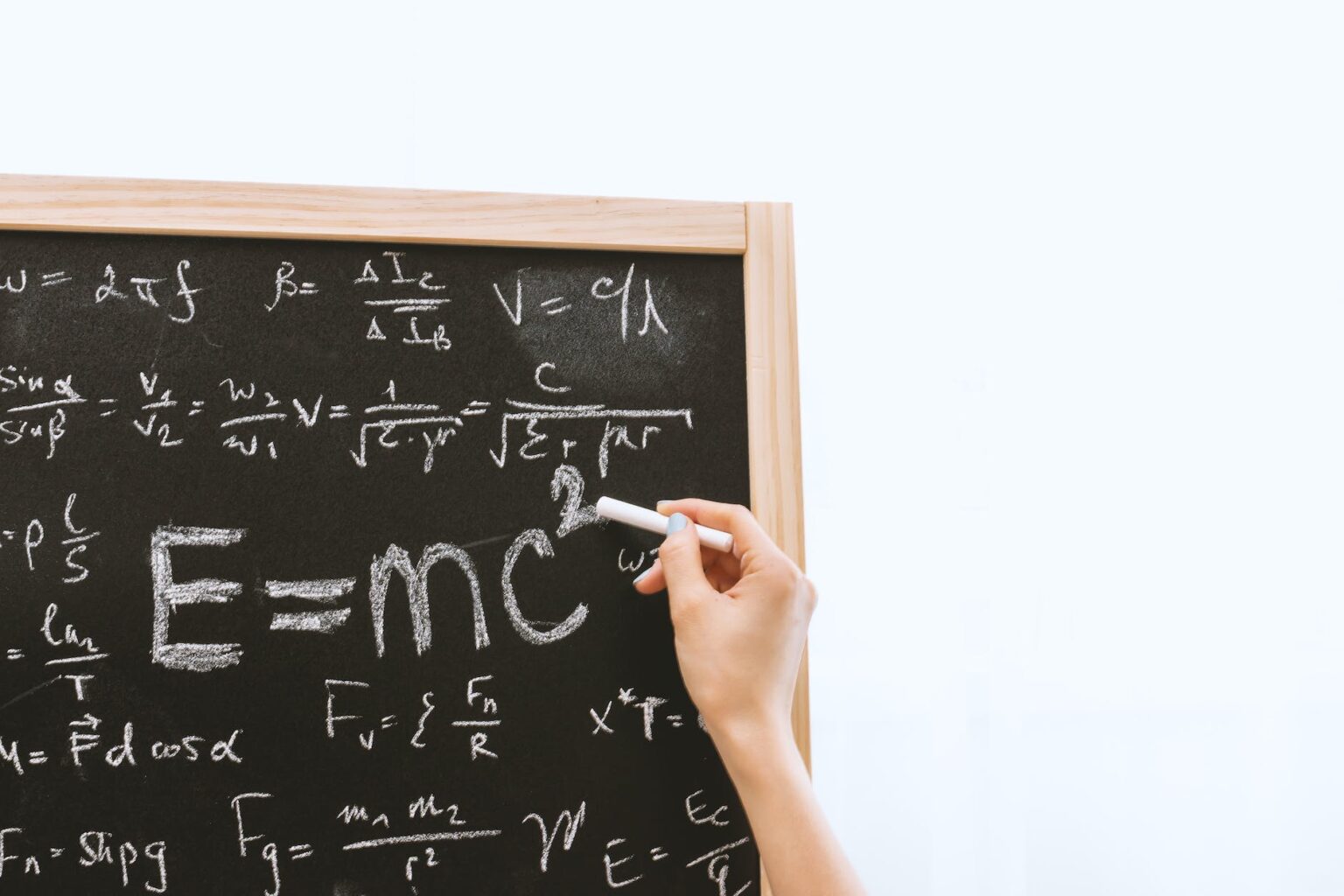 person holding a chalk in front of the chalk board