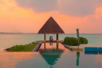 couple under hut beside sea and infinity pool