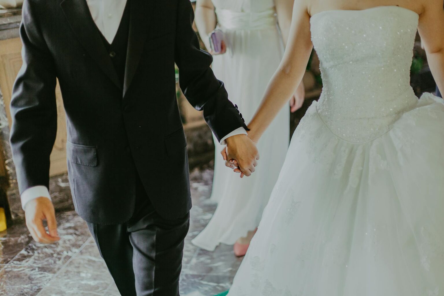 woman wearing white wedding gown holding hands with man while walking