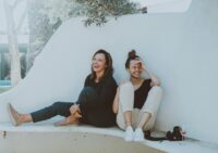 two women sitting on white bench