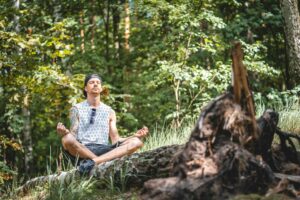 man meditating on a tree log