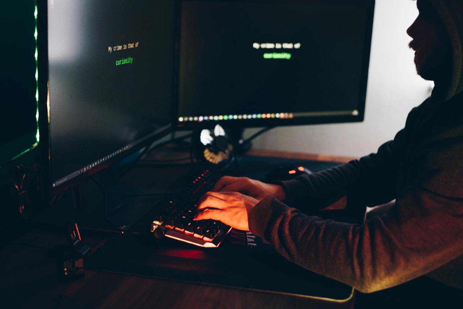 crop hacker silhouette typing on computer keyboard while hacking system