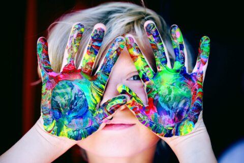 a kid with multicolored hand paint