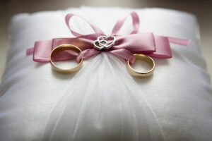 selective focus photography of silver colored engagement ring set with pink bow accent on throw pillow