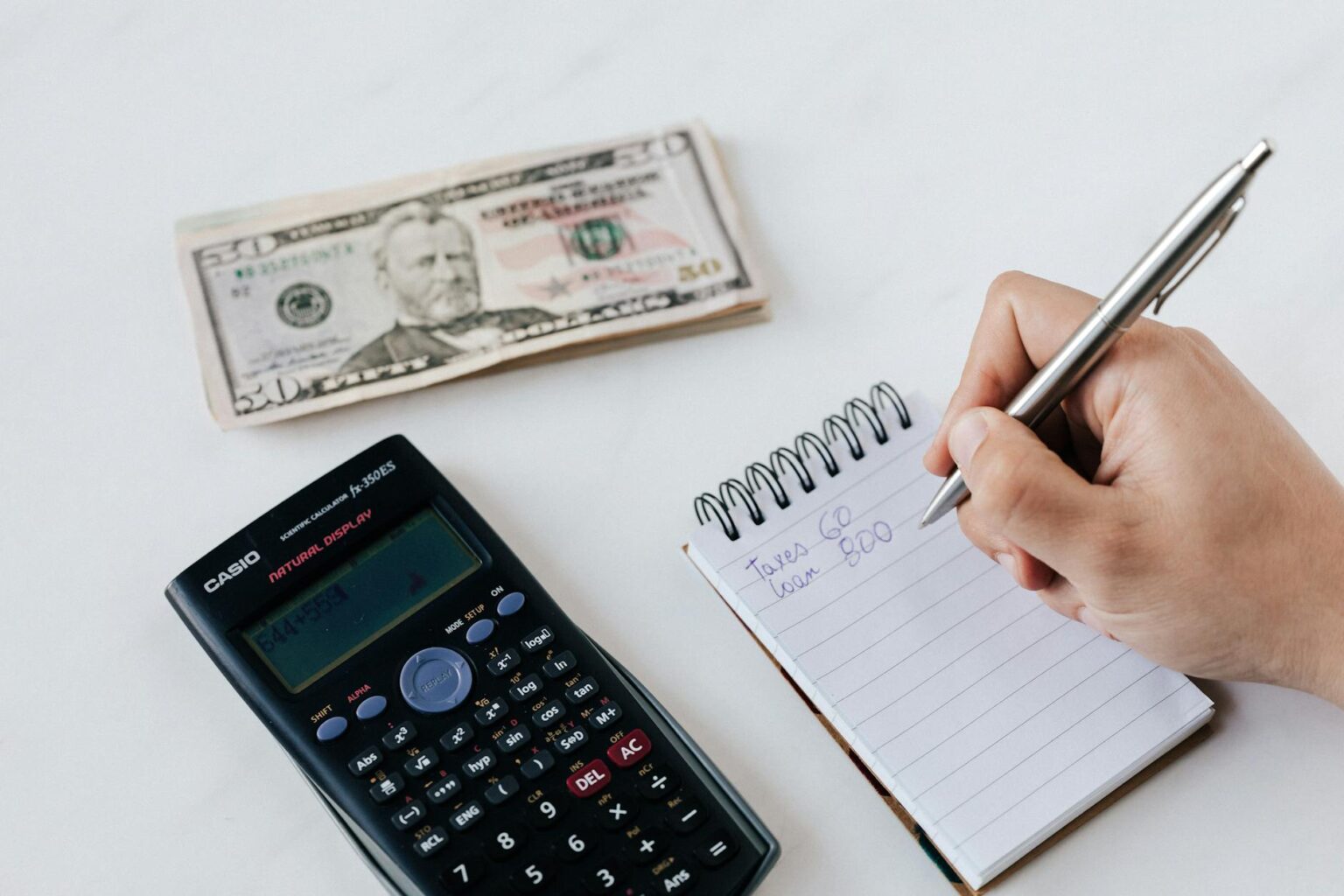 crop anonymous financier planning budget writing numbers in notebook