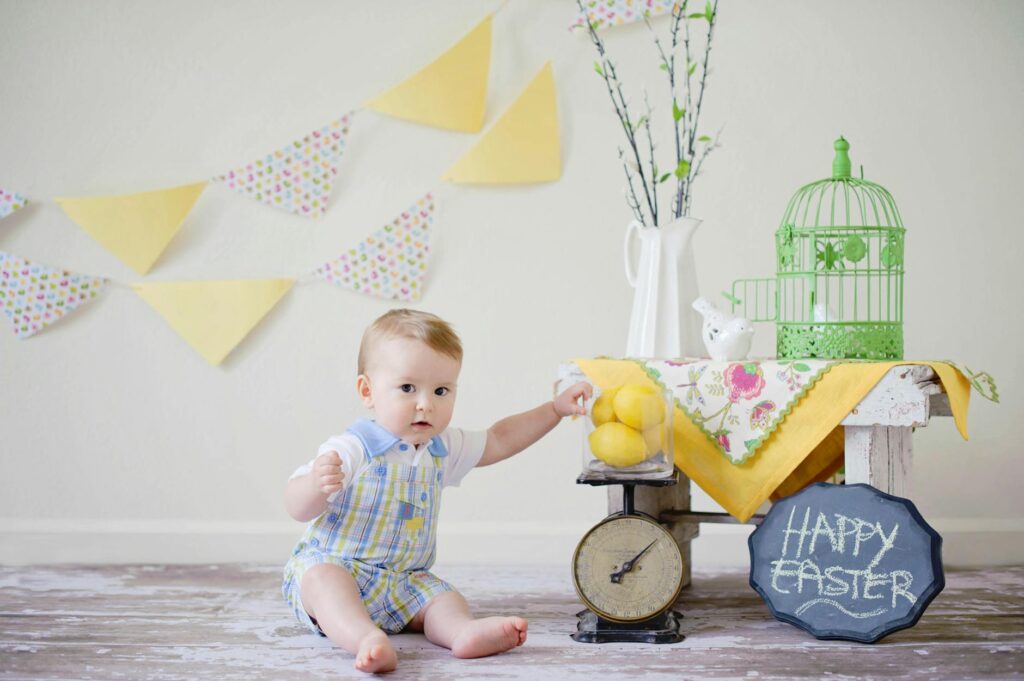 baby sitting on floor surface near table and white wall