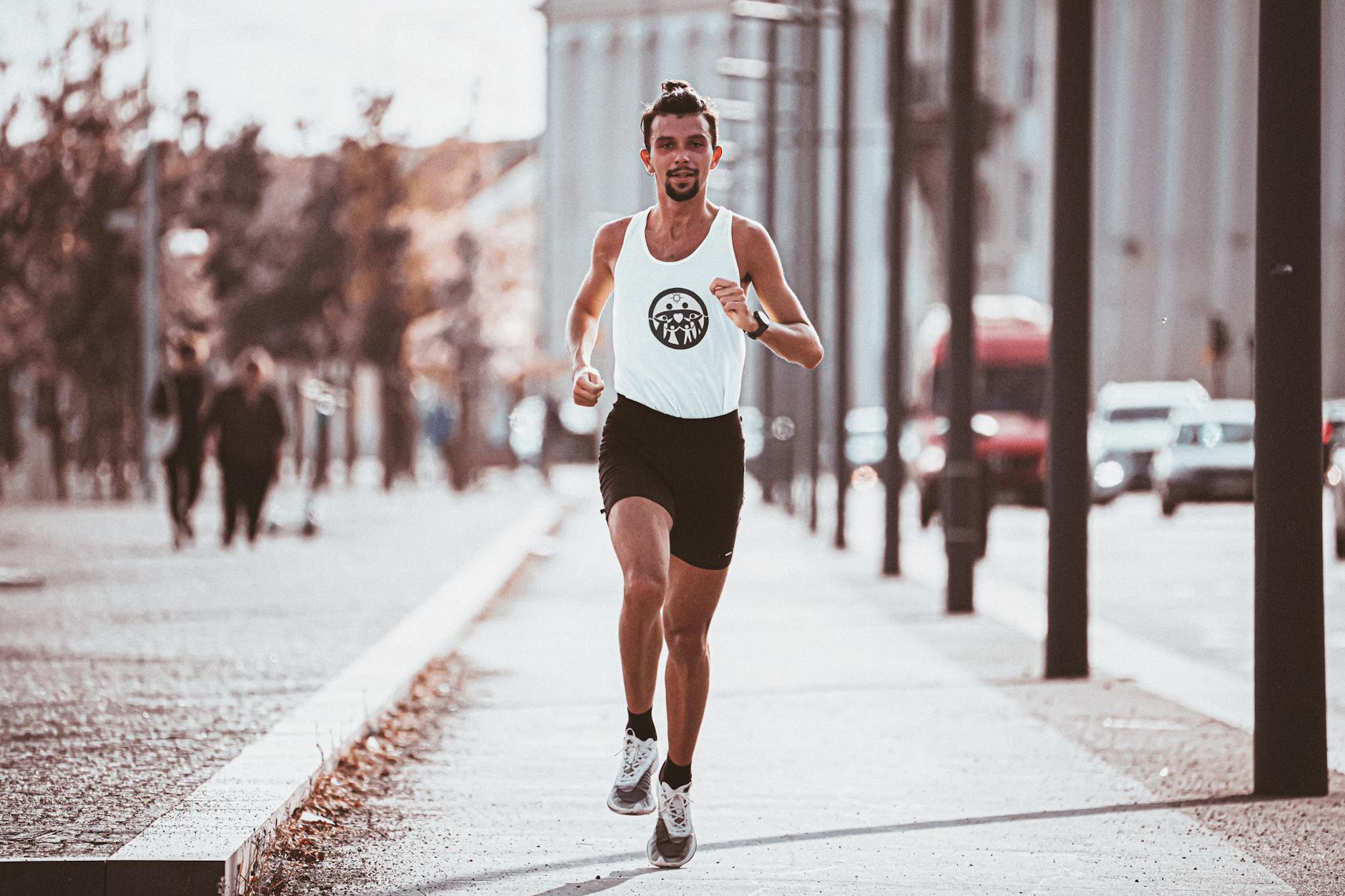 active young man running along asphalt sidewalk