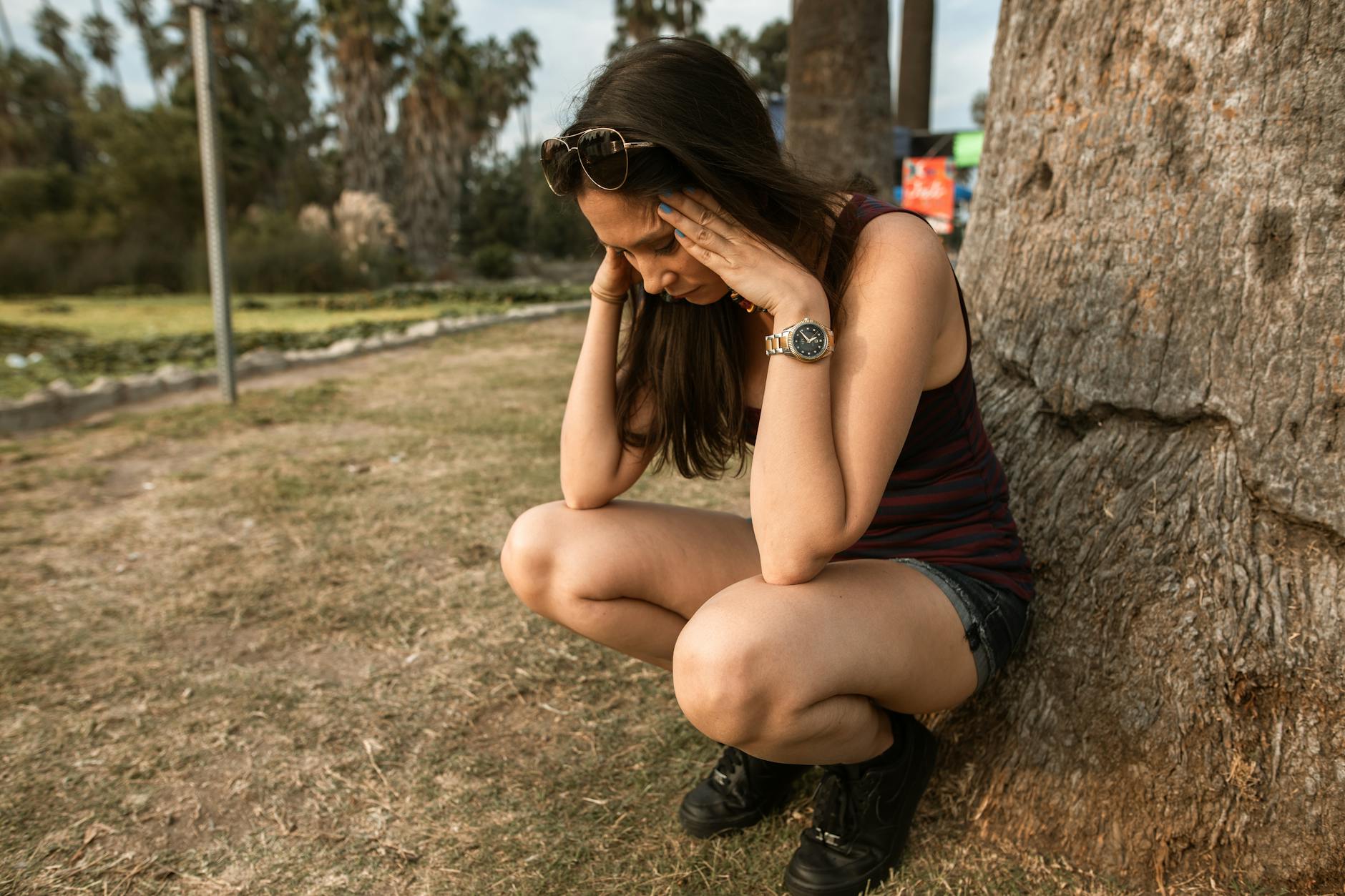 photo of a woman crouching while her hands are on her head