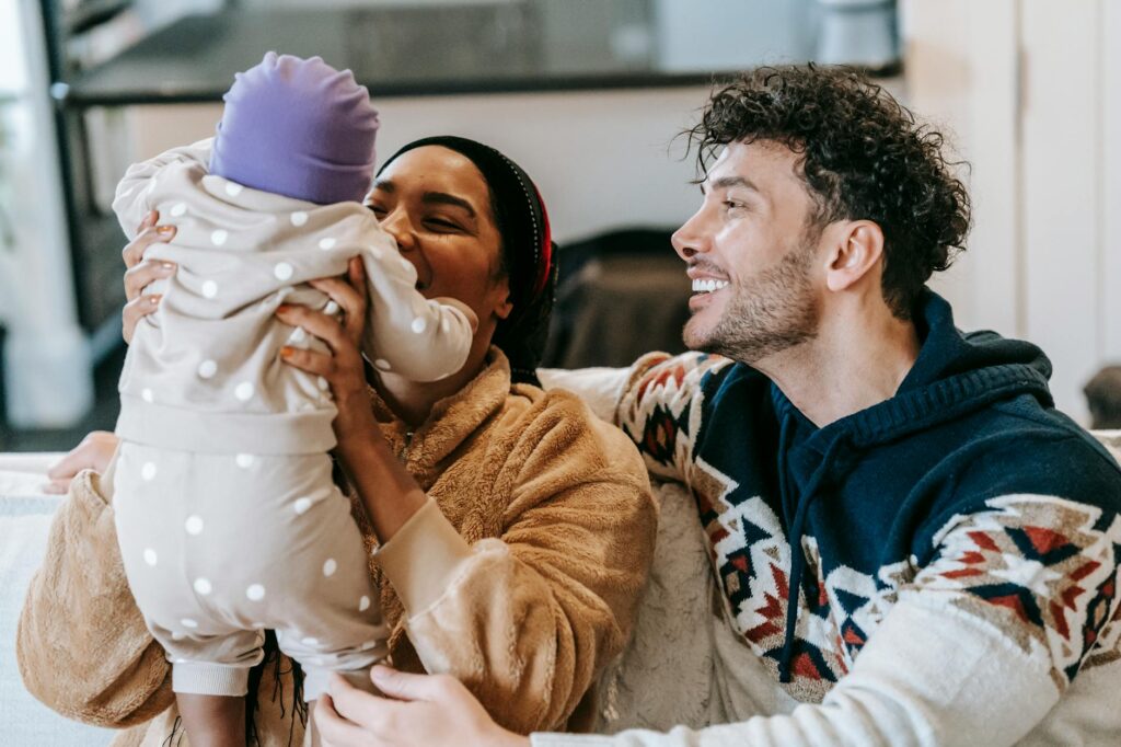 happy multiethnic parents playing with unrecognizable cute baby at home