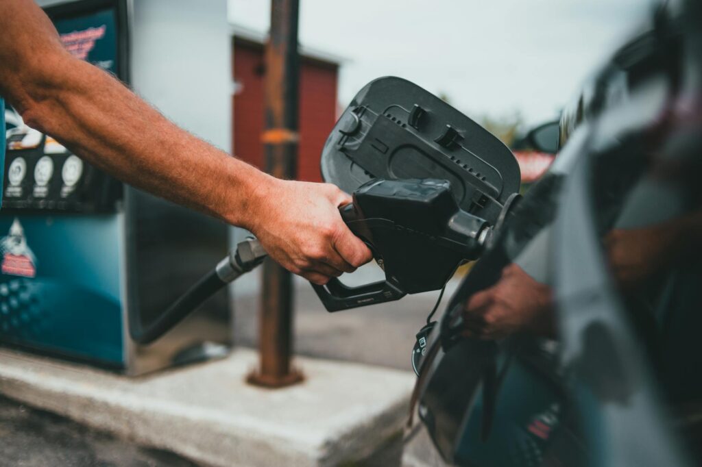 person putting gasoline on a vehicle