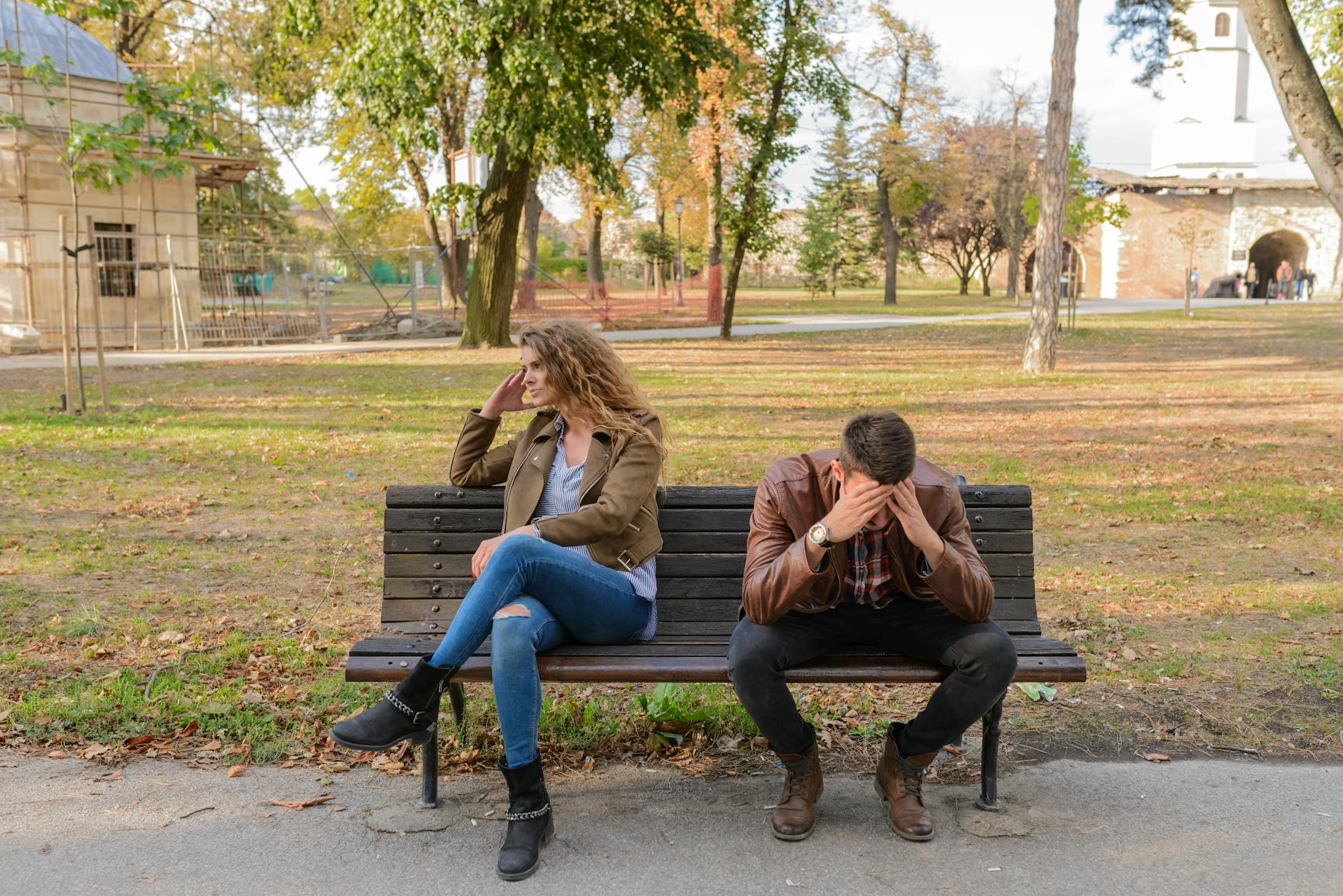 woman and man sitting on brown wooden bench