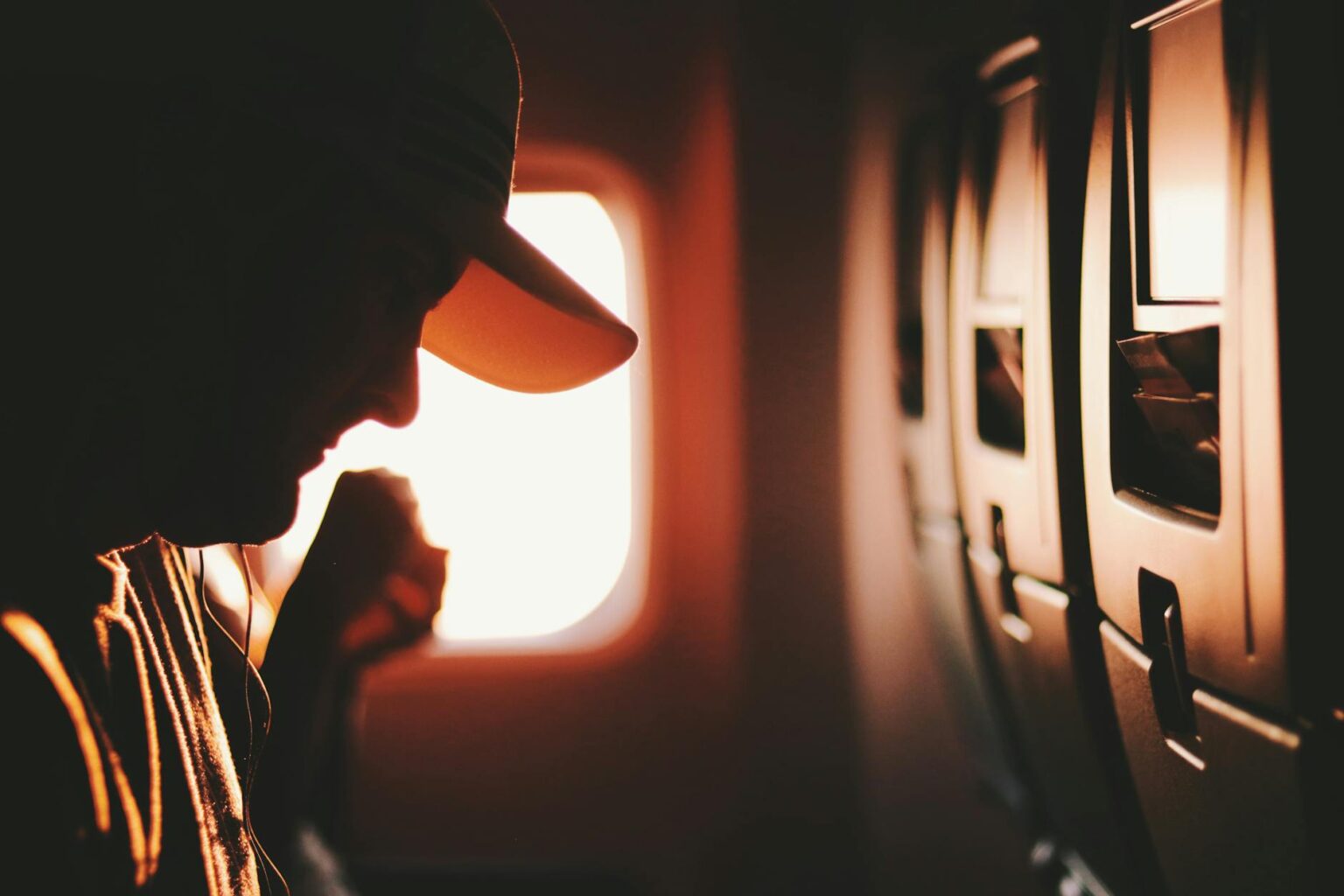 man on airplane seat wearing white cap