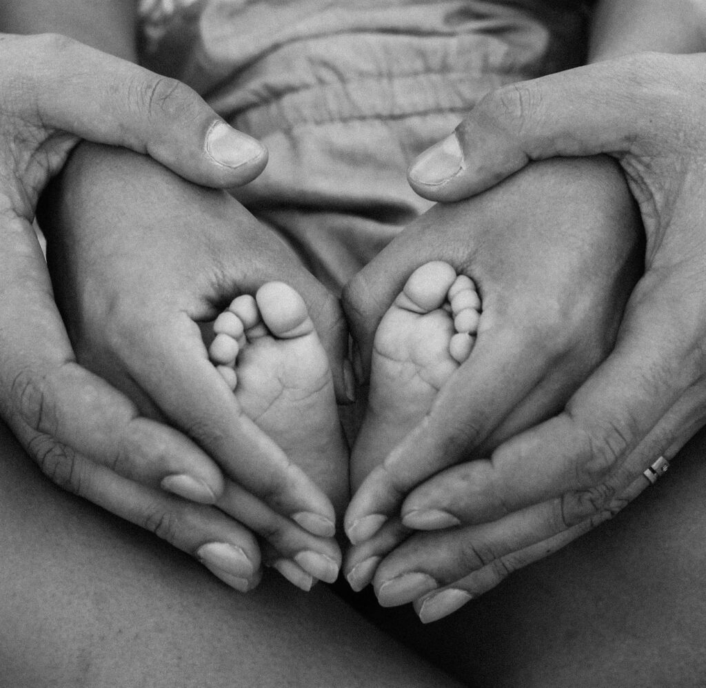 grayscale photo of person holding feet and hands