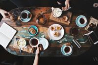 person sitting near table with teacups and plates