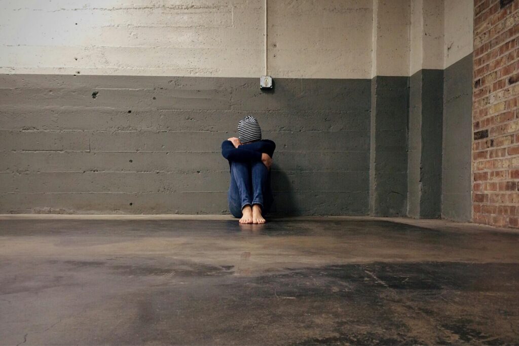 person sitting beside wall inside empty room