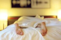 person lying on bed covering white blanket