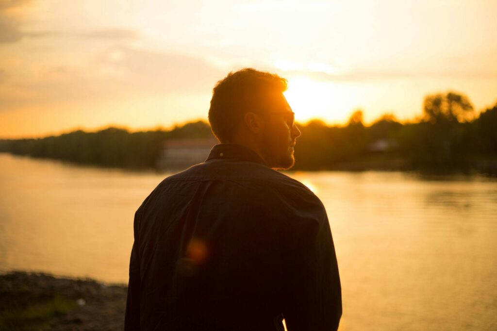 Terazi Erkeği Karakteristik Özellikleri, Elementi ve Değerli Taşları (23 Eylül – 22 Ekim) man sitting near large body of water under clear sky during sunset